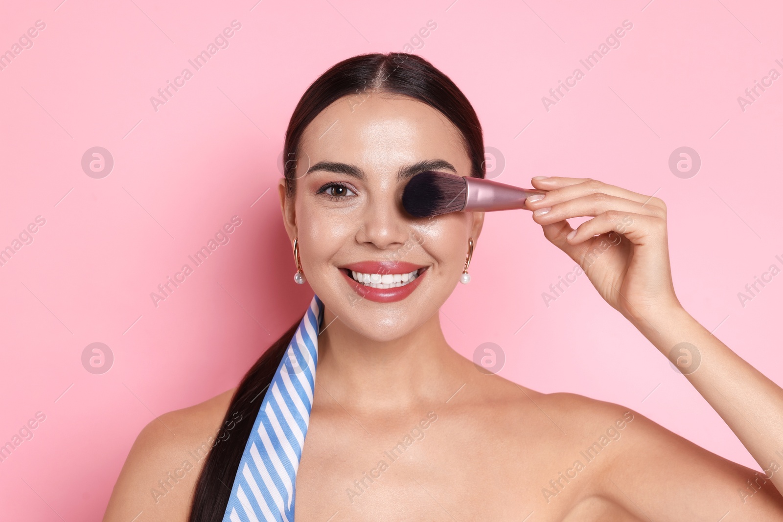 Photo of Beautiful woman with makeup brush on pink background