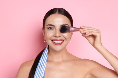 Photo of Beautiful woman with makeup brush on pink background