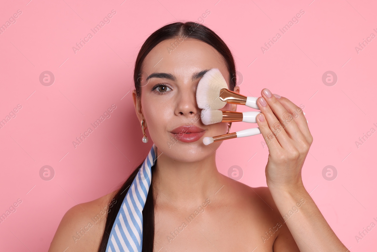 Photo of Beautiful woman with makeup brushes on pink background