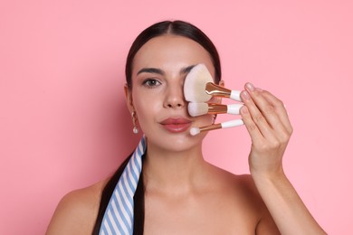 Photo of Beautiful woman with makeup brushes on pink background