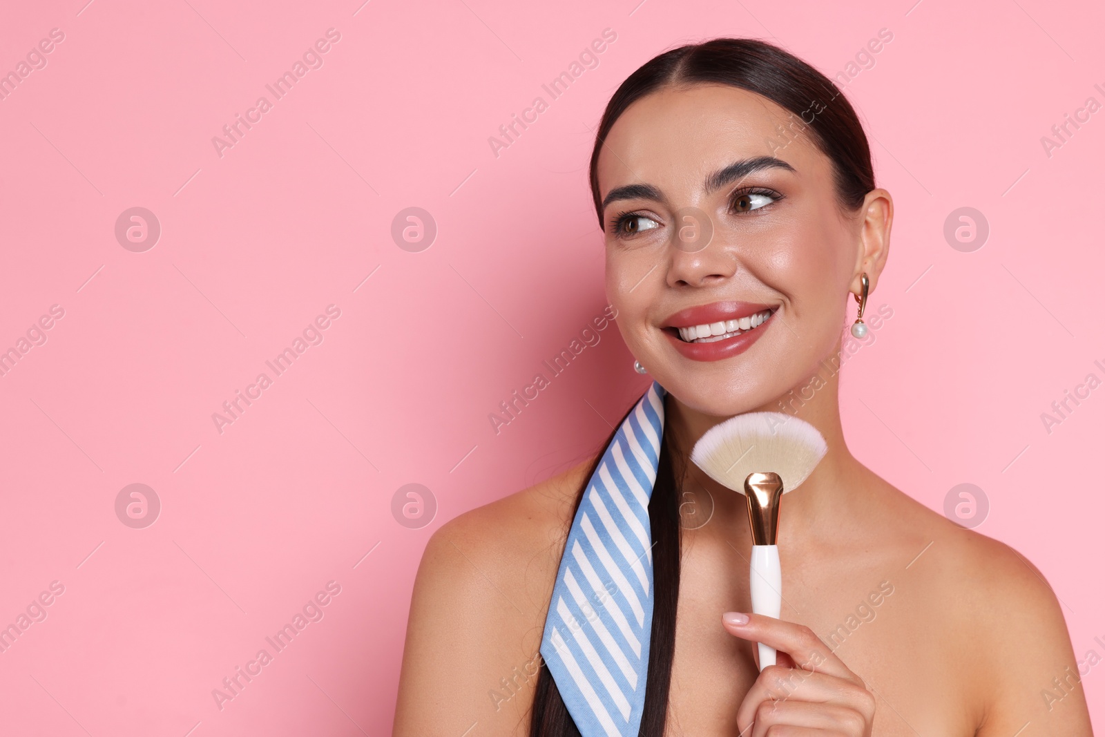 Photo of Beautiful woman with makeup brush on pink background, space for text