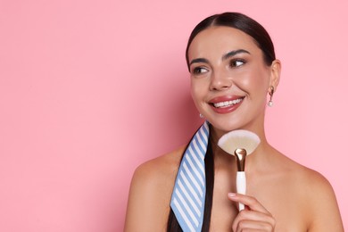 Photo of Beautiful woman with makeup brush on pink background, space for text