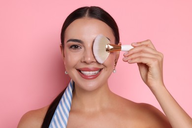 Photo of Beautiful woman with makeup brush on pink background