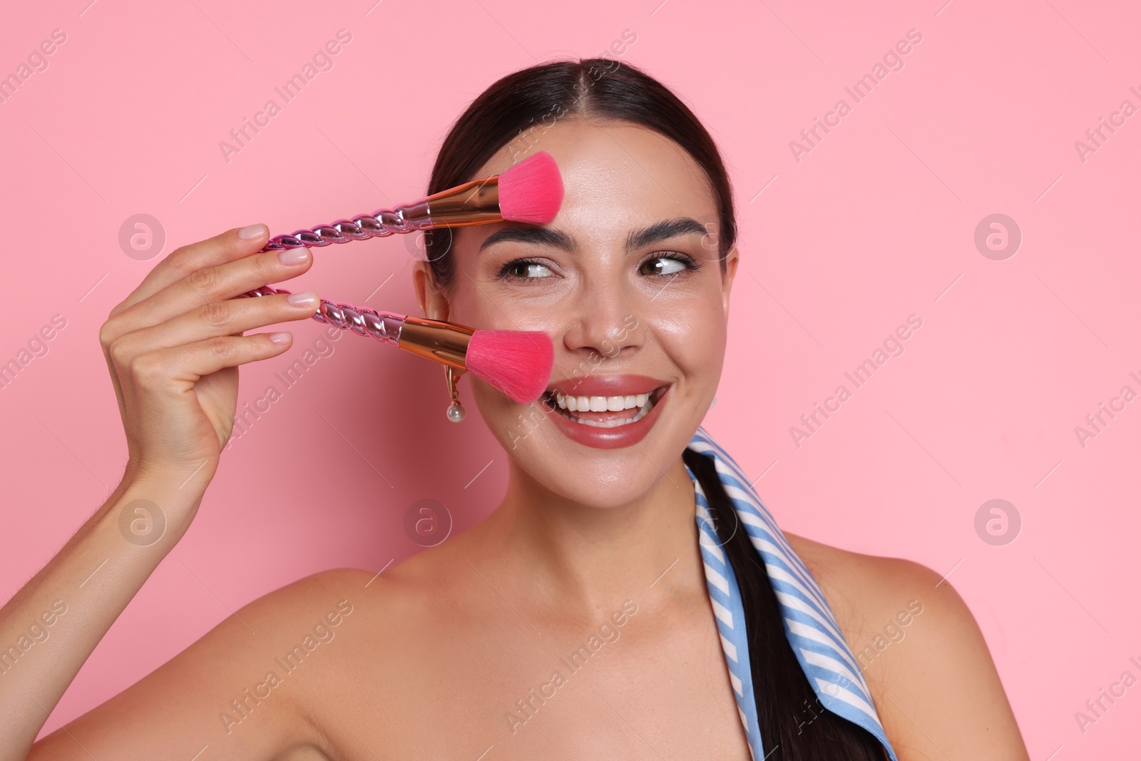 Photo of Beautiful woman with makeup brushes on pink background
