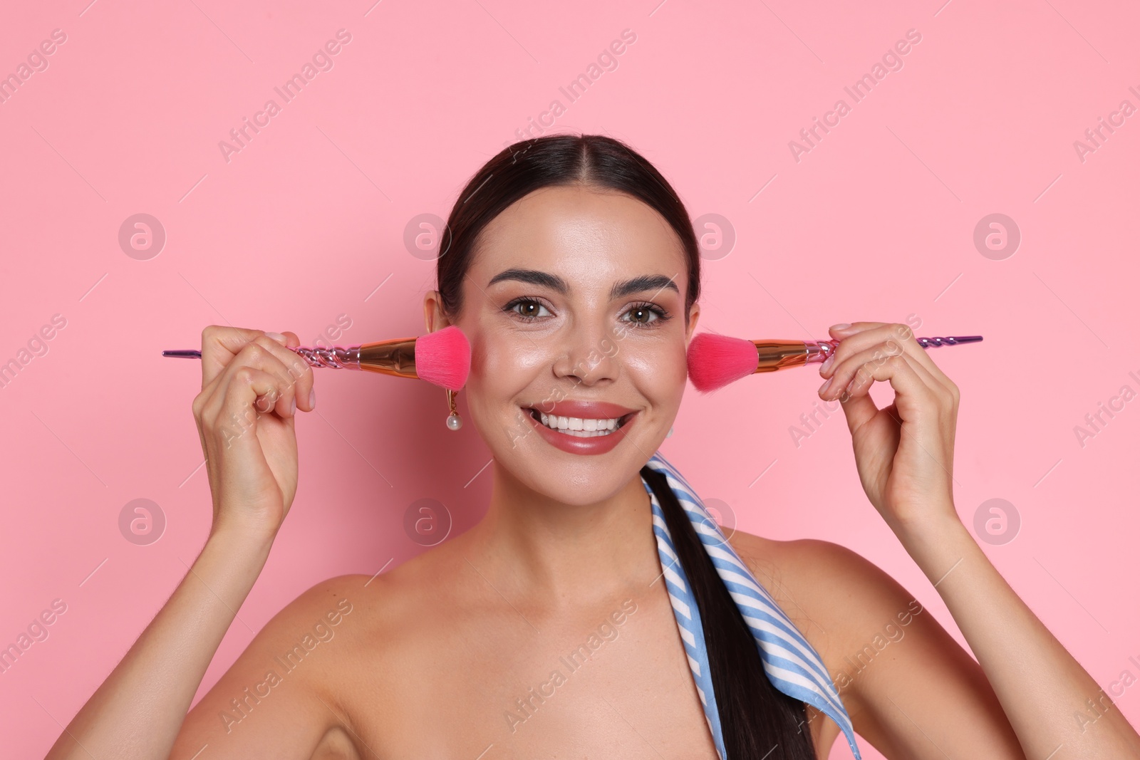 Beautiful woman with makeup brushes on pink background Photo of Beautiful woman with makeup brushes on pink background