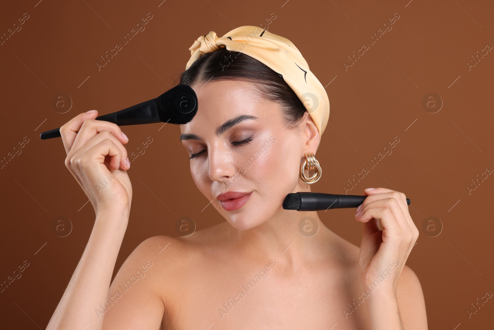 Beautiful woman with makeup brushes on brown background Photo of Beautiful woman with makeup brushes on brown background