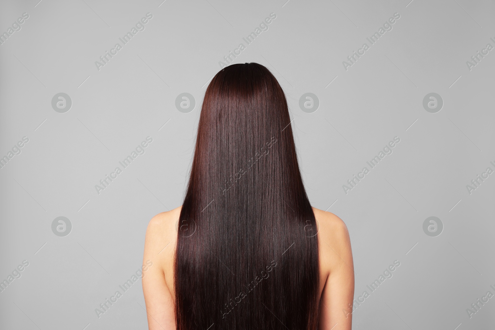 Photo of Woman with beautiful smooth hair after lamination procedure on light grey background, back view