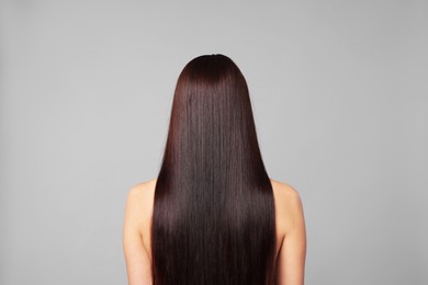 Photo of Woman with beautiful smooth hair after lamination procedure on light grey background, back view
