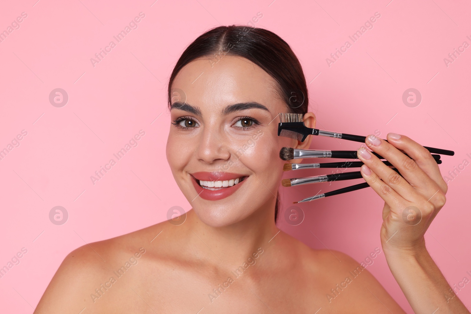 Beautiful woman with makeup brushes on pink background Photo of Beautiful woman with makeup brushes on pink background