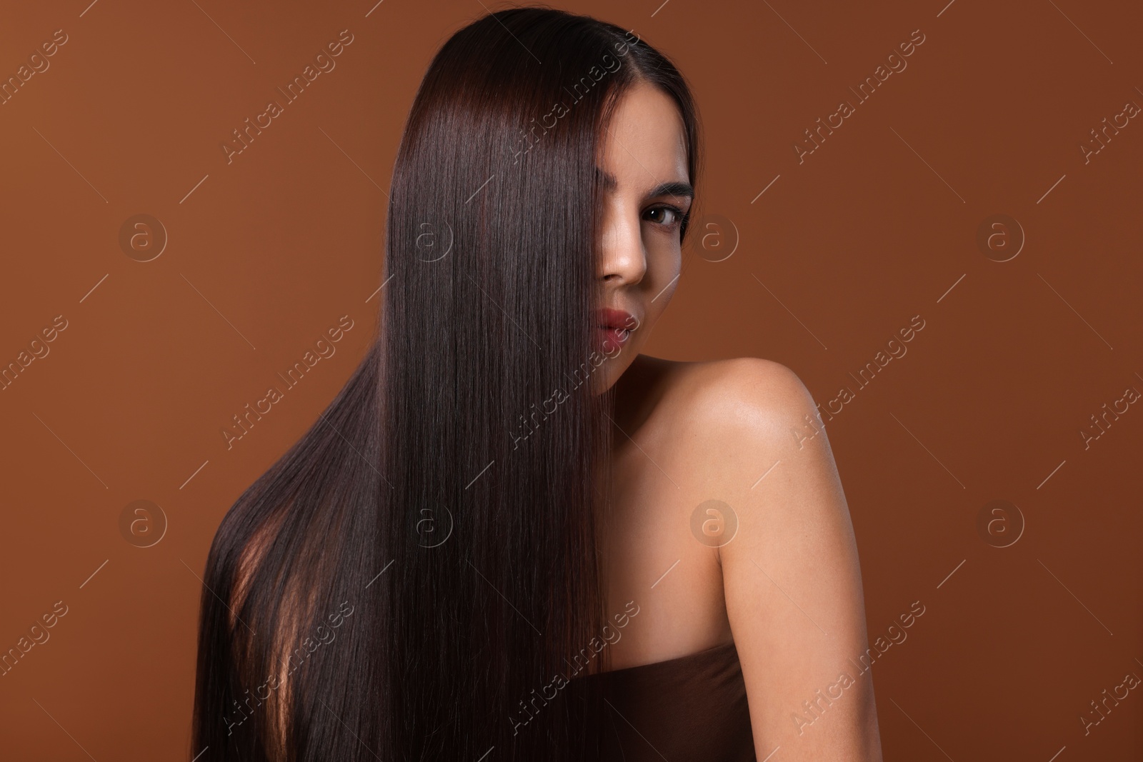 Photo of Woman with beautiful smooth hair after lamination procedure on brown background