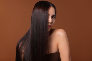 Photo of Woman with beautiful smooth hair after lamination procedure on brown background