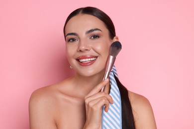 Photo of Beautiful woman with makeup brush on pink background