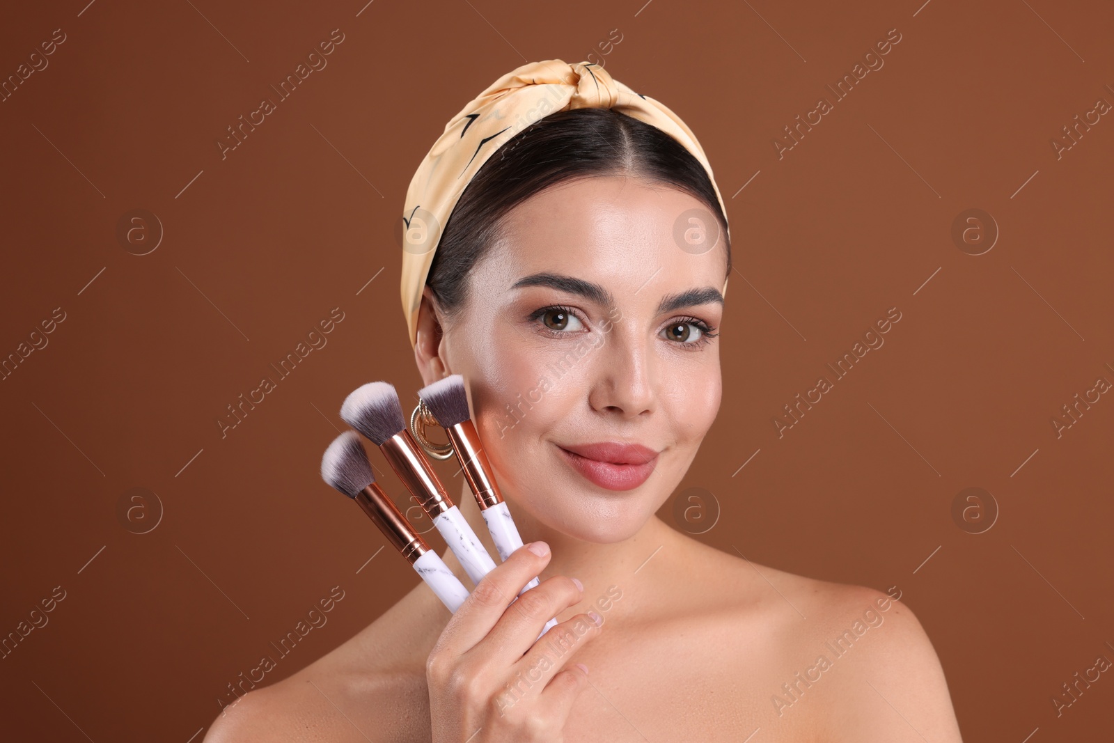 Beautiful woman with makeup brushes on brown background Photo of Beautiful woman with makeup brushes on brown background
