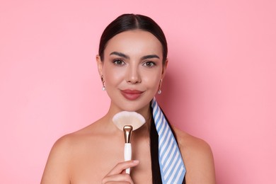 Photo of Beautiful woman with makeup brush on pink background