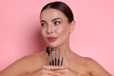 Photo of Beautiful woman with makeup brushes on pink background