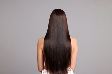 Photo of Woman with beautiful smooth hair after lamination procedure on light grey background, back view