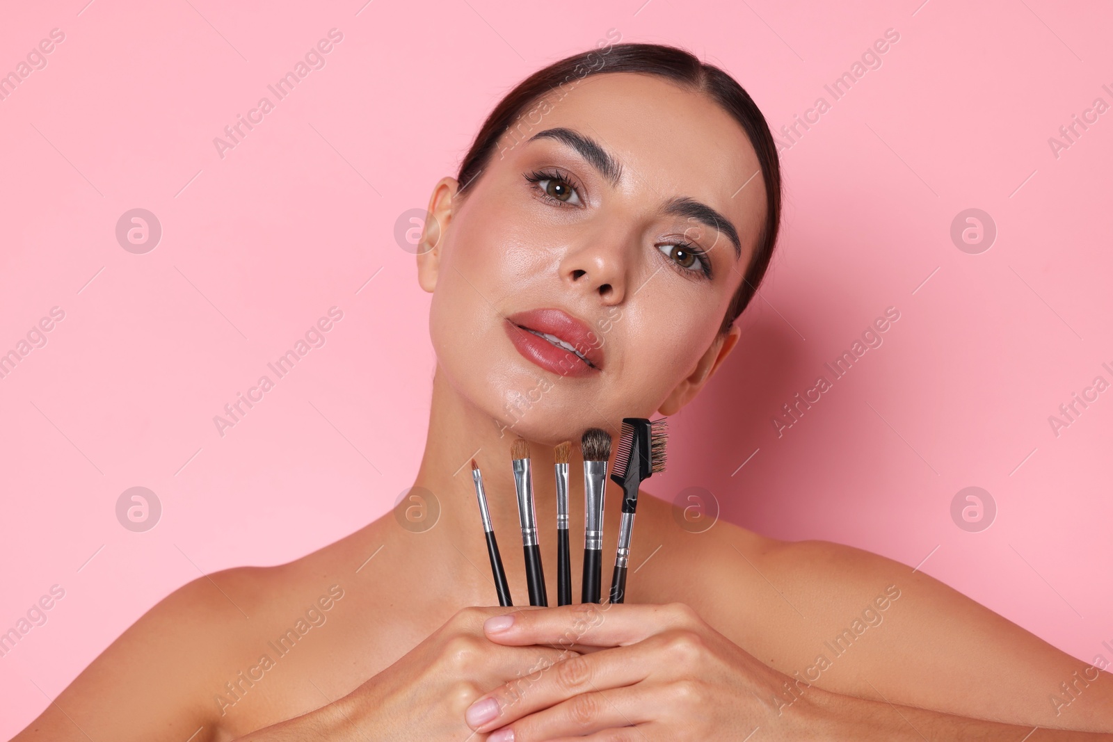 Beautiful woman with makeup brushes on pink background Photo of Beautiful woman with makeup brushes on pink background