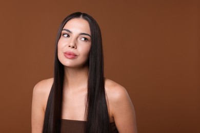 Photo of Woman with beautiful smooth hair after lamination procedure on brown background, space for text