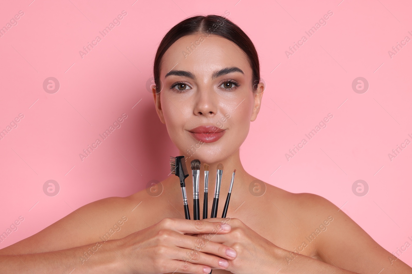 Beautiful woman with makeup brushes on pink background Photo of Beautiful woman with makeup brushes on pink background