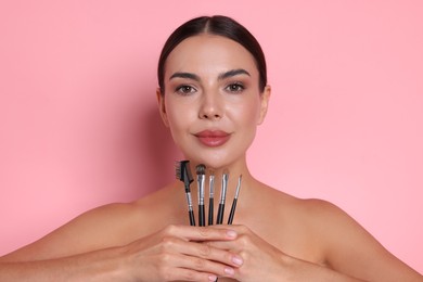 Photo of Beautiful woman with makeup brushes on pink background