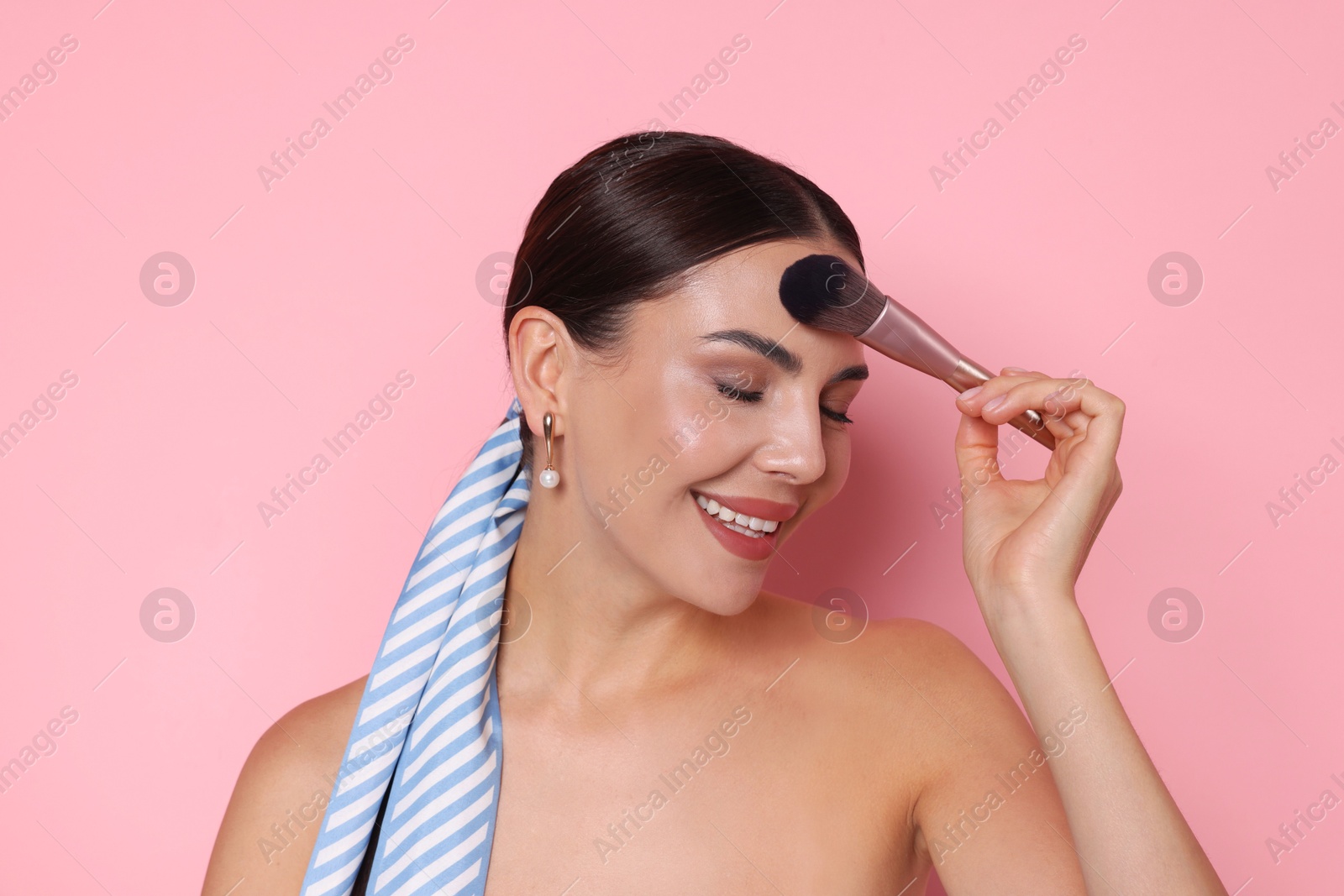 Photo of Beautiful woman applying makeup with brush on pink background