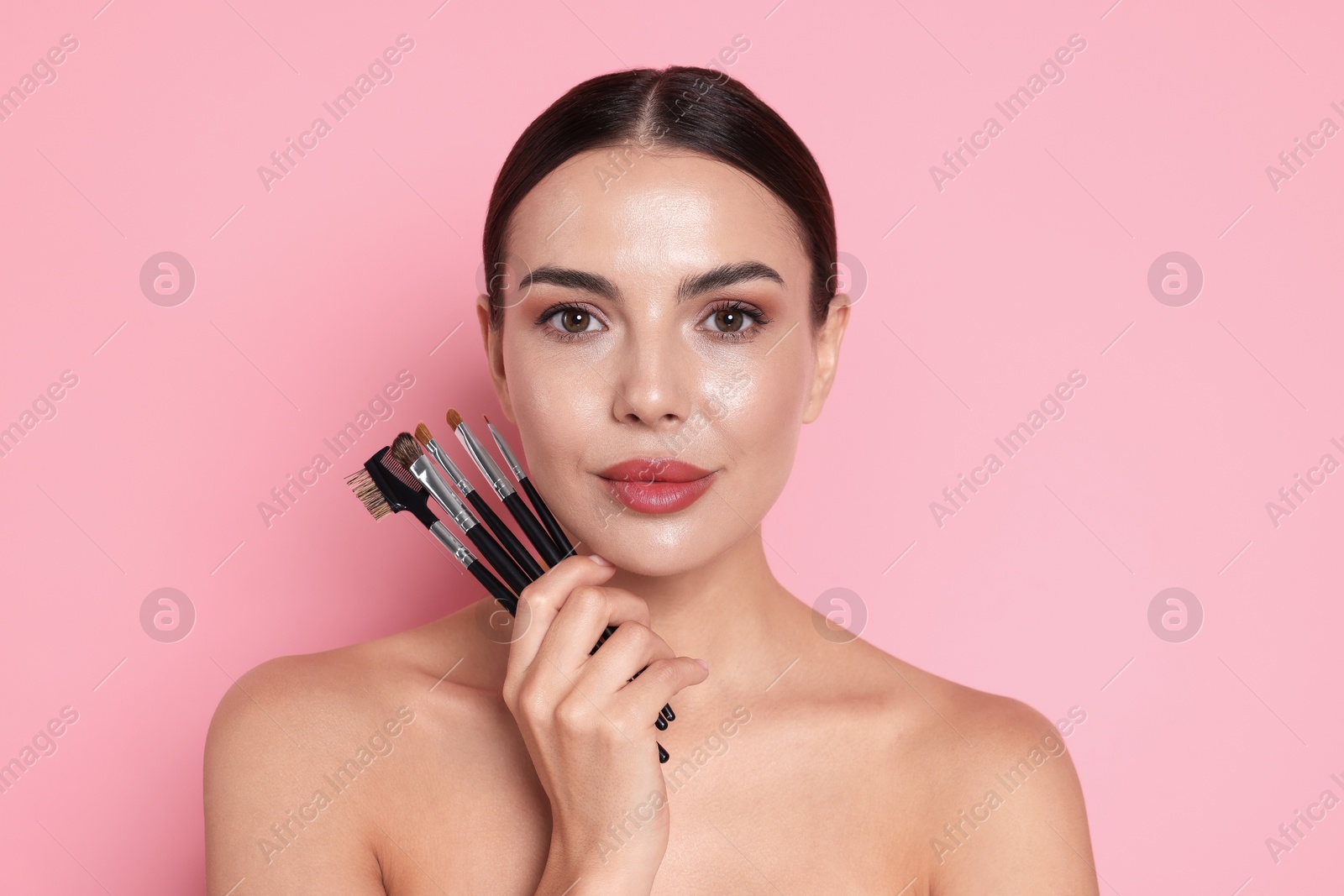 Beautiful woman with makeup brushes on pink background Photo of Beautiful woman with makeup brushes on pink background