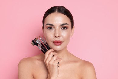 Photo of Beautiful woman with makeup brushes on pink background