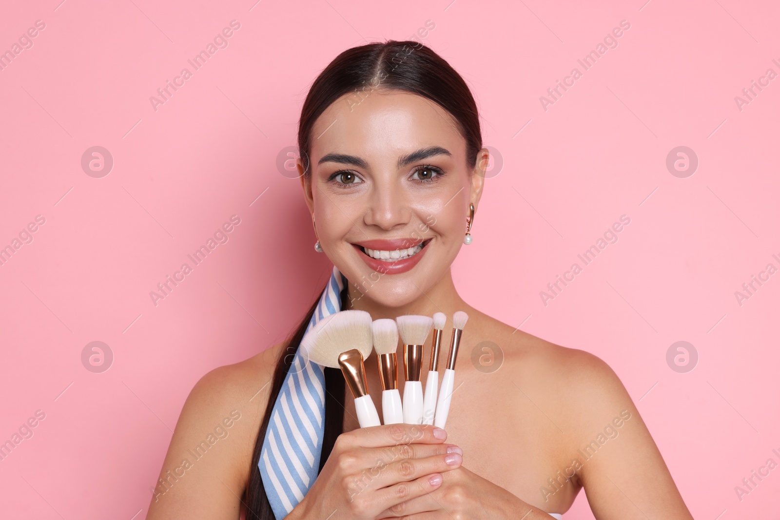 Beautiful woman with makeup brushes on pink background Photo of Beautiful woman with makeup brushes on pink background