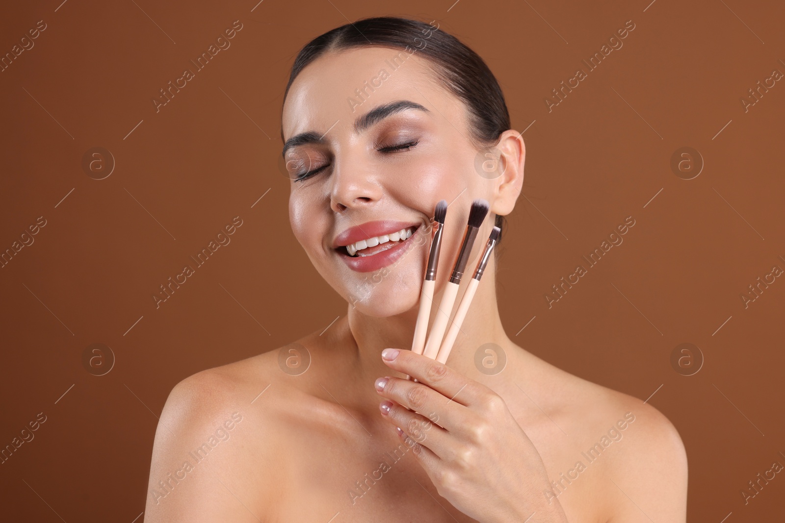 Beautiful woman with makeup brushes on brown background Photo of Beautiful woman with makeup brushes on brown background