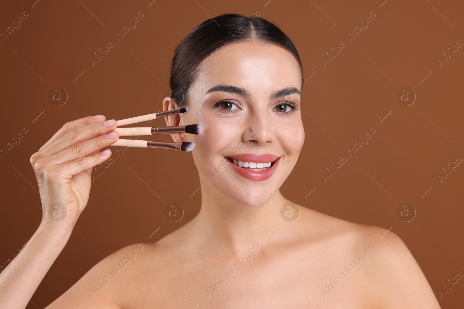 Beautiful woman with makeup brushes on brown background Photo of Beautiful woman with makeup brushes on brown background