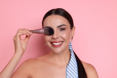 Photo of Beautiful woman with makeup brush on pink background