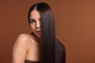 Photo of Woman with beautiful smooth hair after lamination procedure on brown background, space for text