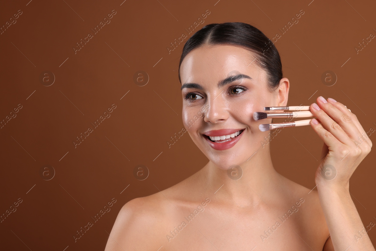 Beautiful woman with makeup brushes on brown background, space for text Photo of Beautiful woman with makeup brushes on brown background, space for text