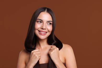 Photo of Woman with beautiful smooth hair after lamination procedure on brown background
