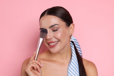Photo of Beautiful woman with makeup brush on pink background