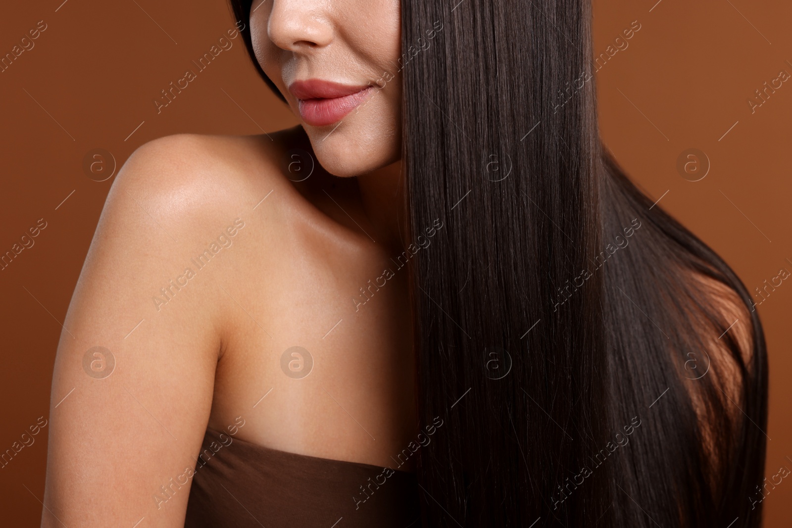 Photo of Woman with beautiful smooth hair after lamination procedure on brown background, closeup