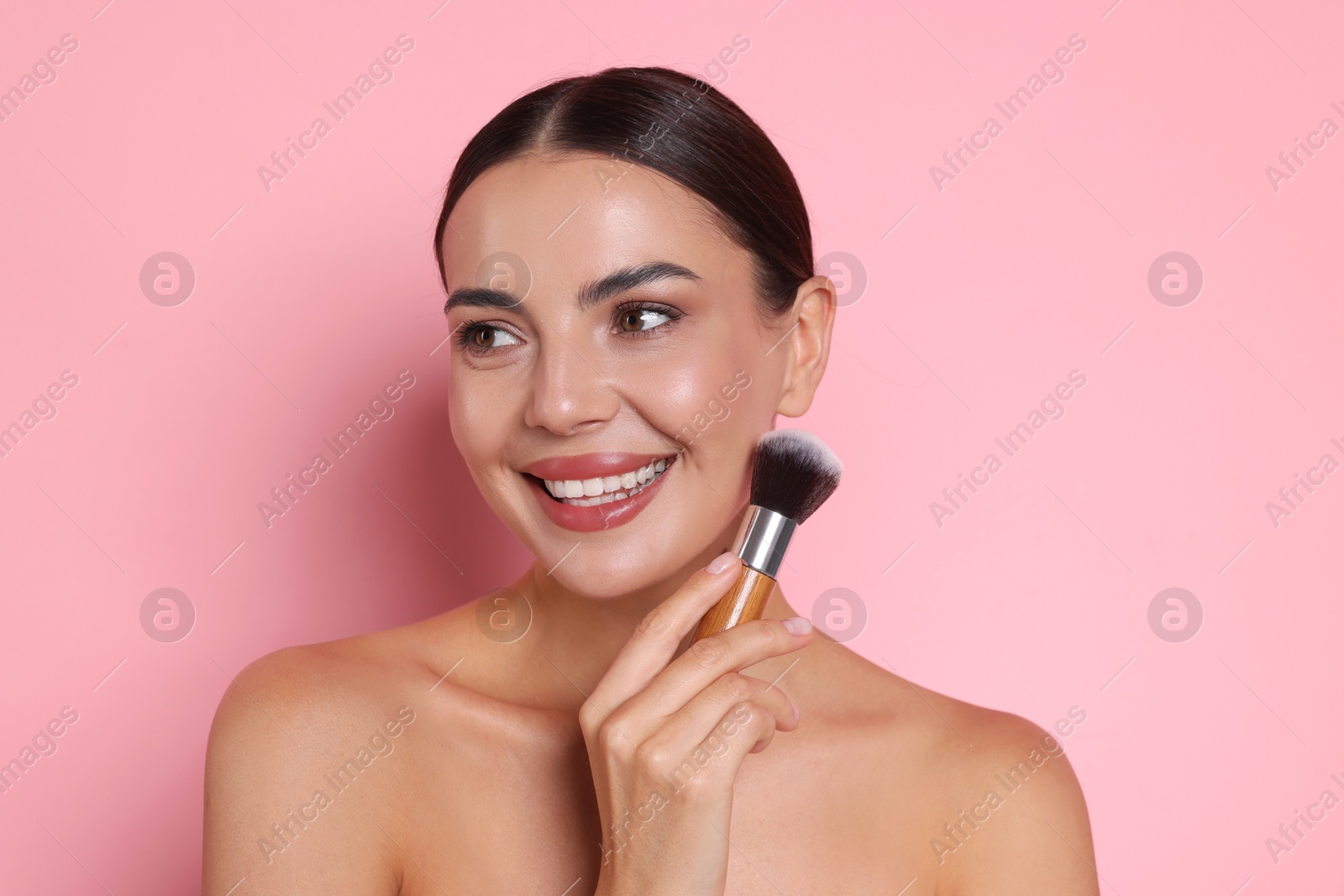 Beautiful woman with makeup brush on pink background Photo of Beautiful woman with makeup brush on pink background