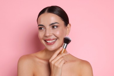 Photo of Beautiful woman with makeup brush on pink background