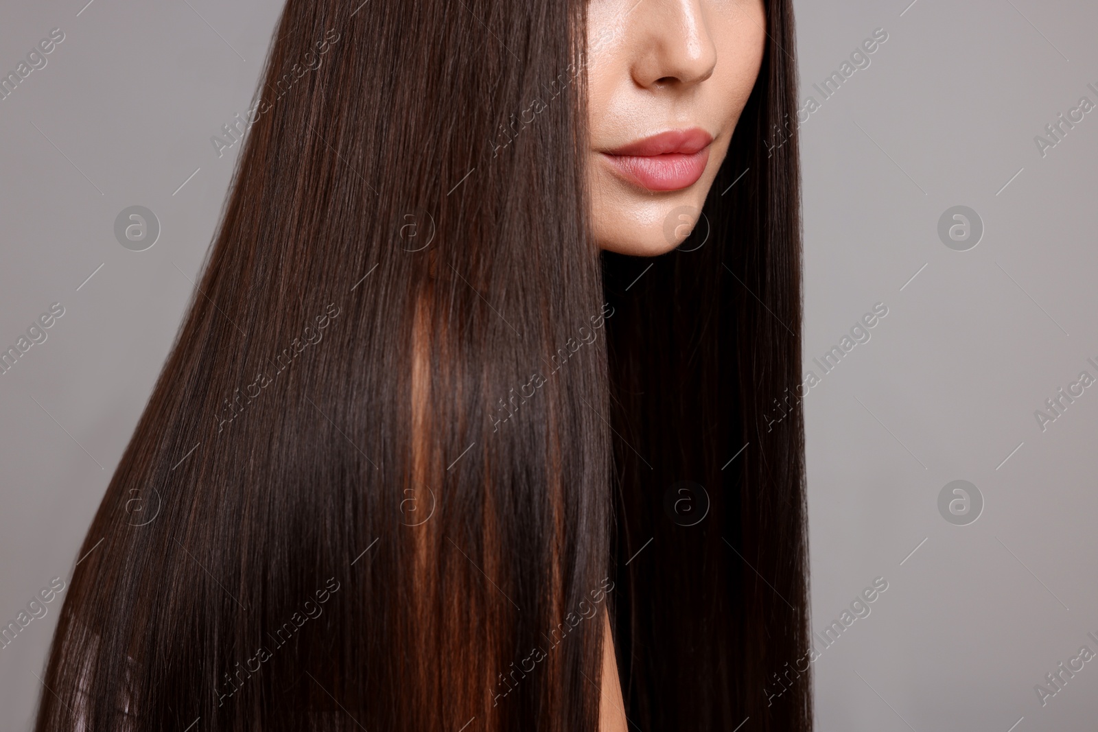 Photo of Woman with beautiful smooth hair after lamination procedure on light grey background, closeup