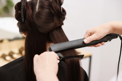Photo of Hairdresser laminating woman's hair in salon, closeup