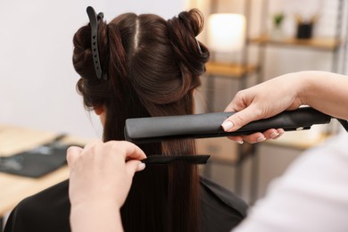 Photo of Hairdresser laminating woman's hair in salon, closeup