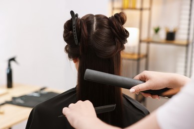 Photo of Hairdresser laminating woman's hair in salon, closeup