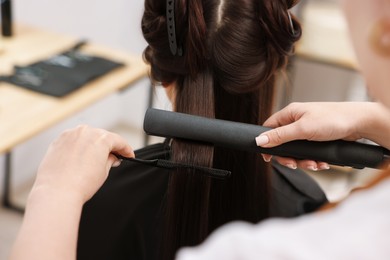 Photo of Hairdresser laminating woman's hair in salon, closeup