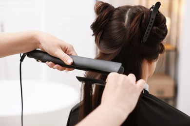 Photo of Hairdresser laminating woman's hair in salon, closeup