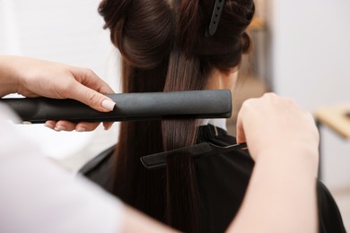 Photo of Hairdresser laminating woman's hair in salon, closeup