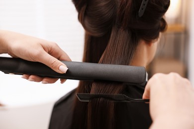 Photo of Hairdresser laminating woman's hair in salon, closeup
