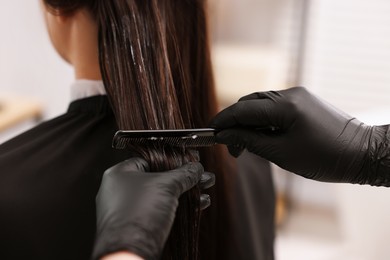 Photo of Hairdresser laminating woman's hair in salon, closeup