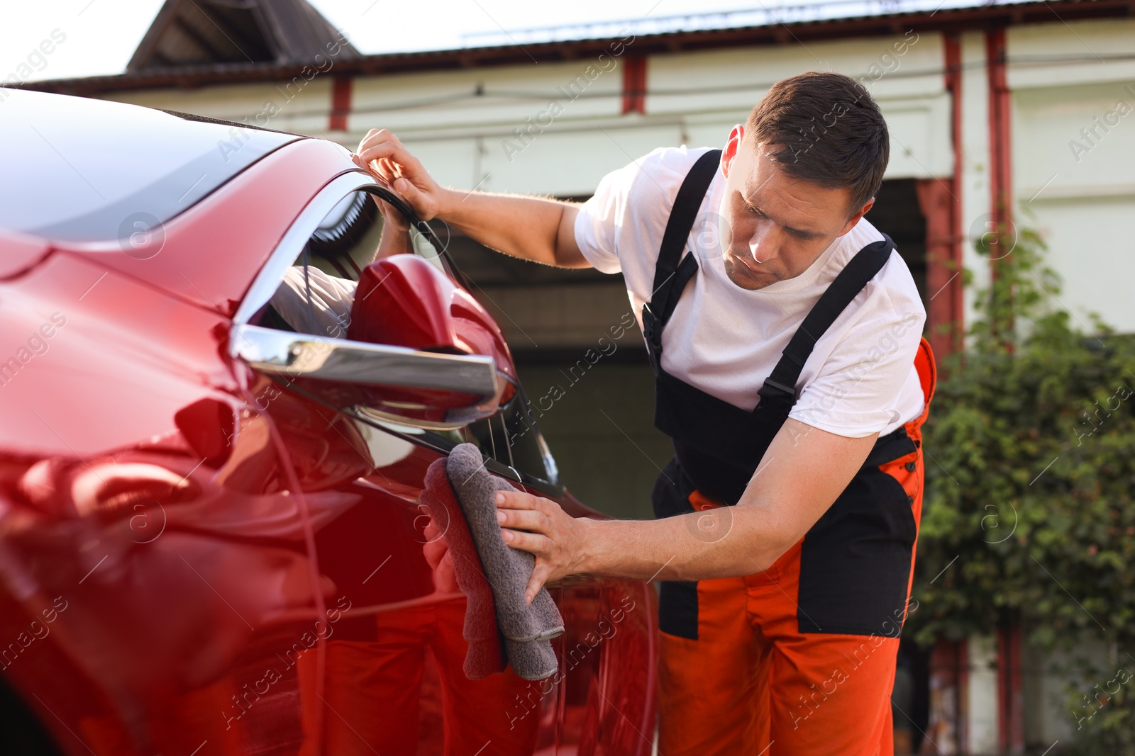 Man wiping car with grey microfiber rag outdoors Photo of Man wiping car with grey microfiber rag outdoors