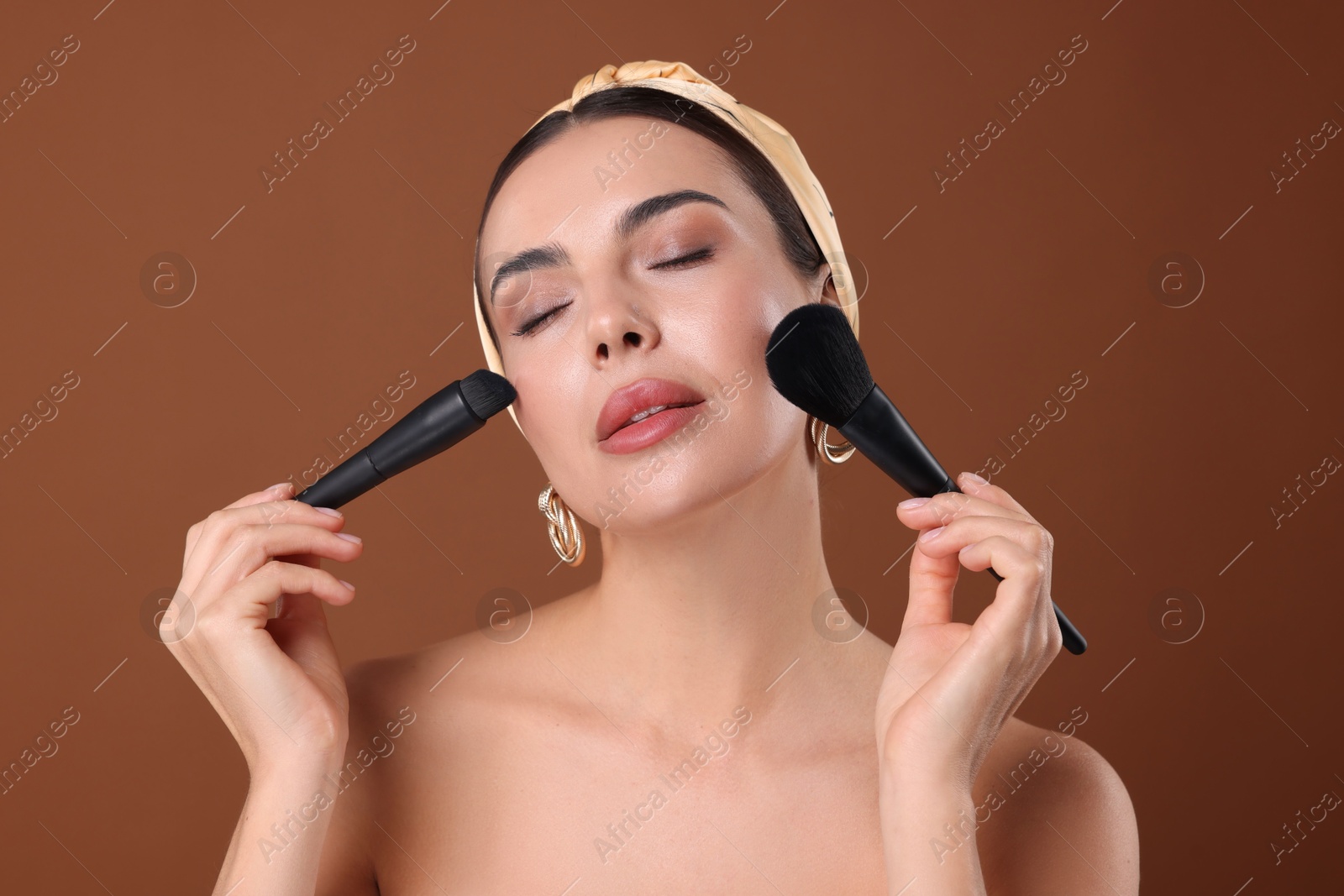 Beautiful woman with makeup brushes on brown background Photo of Beautiful woman with makeup brushes on brown background