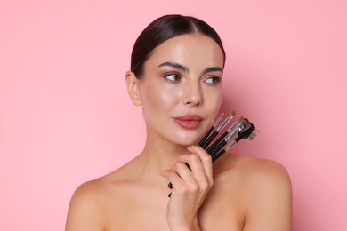 Photo of Beautiful woman with makeup brushes on pink background